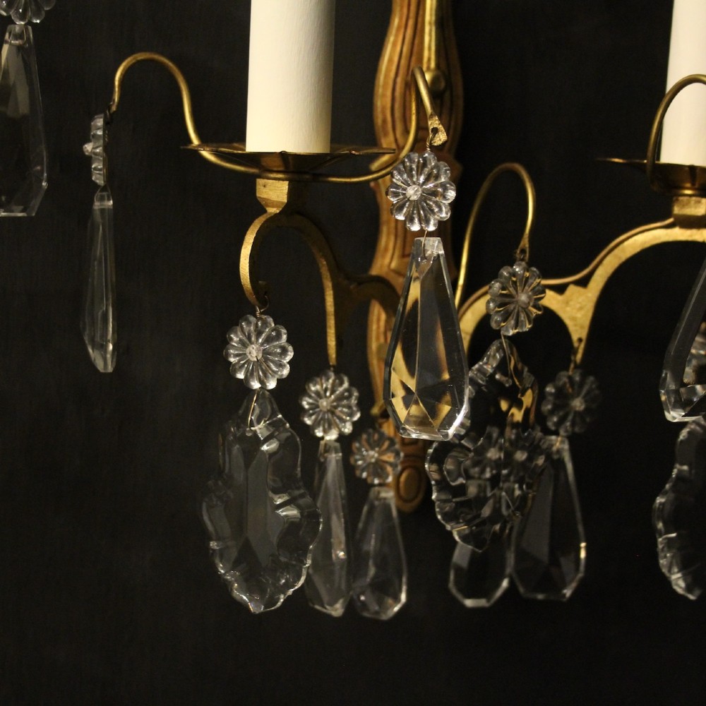 A pair of French gilded wall lights featuring twin candle-style bulb sockets, scrolling metal arms, and hanging faceted crystal droplets. View VI