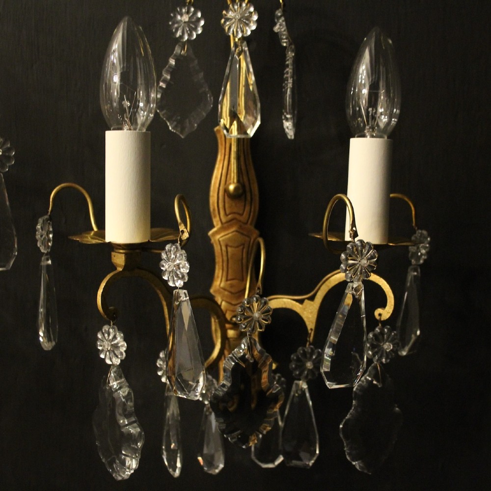 A pair of French gilded wall lights featuring twin candle-style bulb sockets, scrolling metal arms, and hanging faceted crystal droplets. View VIII