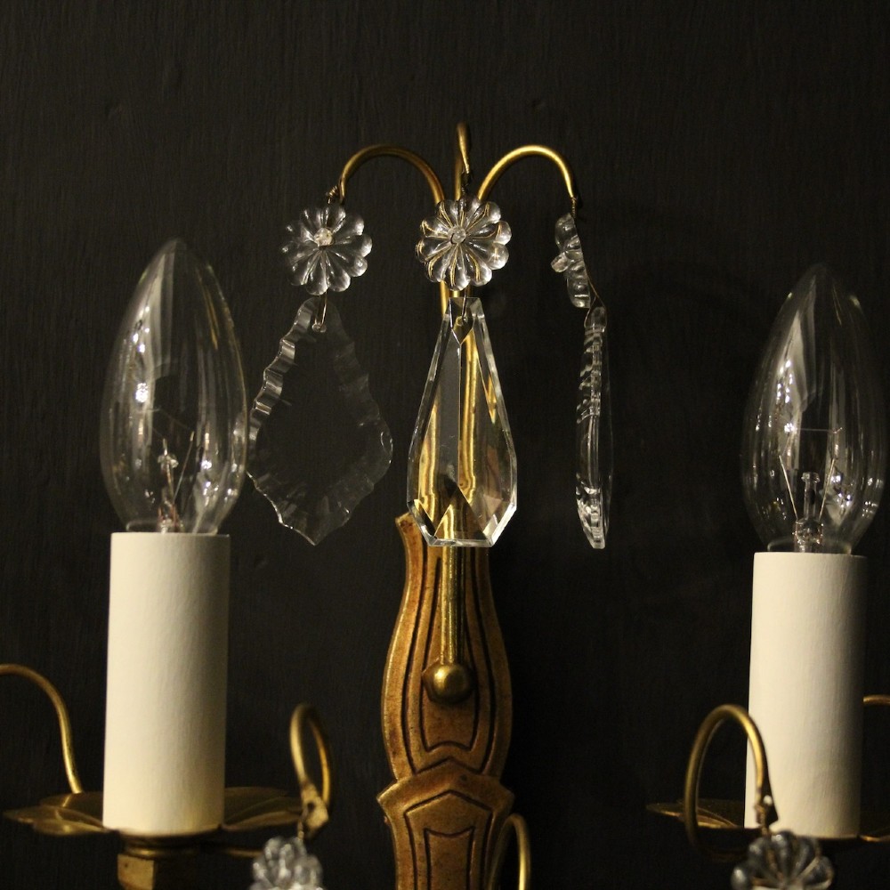 A pair of French gilded wall lights featuring twin candle-style bulb sockets, scrolling metal arms, and hanging faceted crystal droplets. View IX