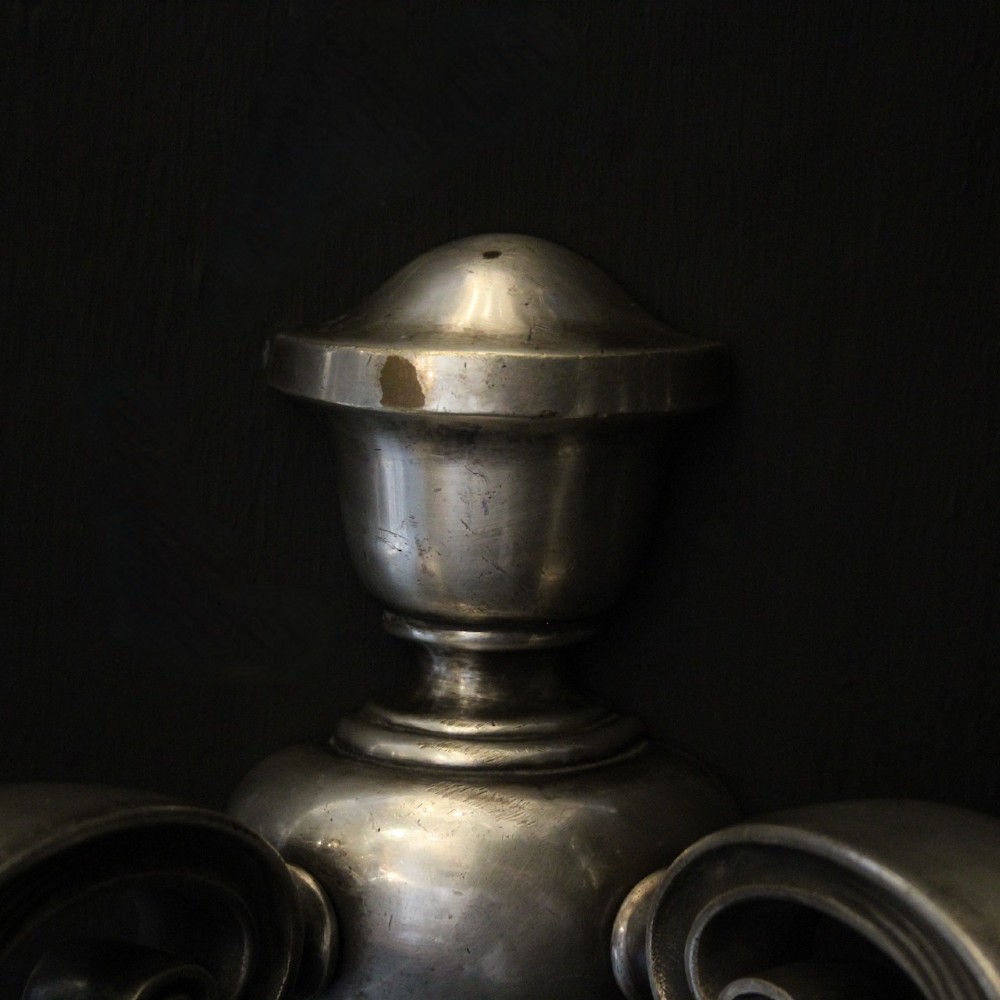 A pair of antique silver-plated twin-arm wall lights with scrolled branches, turned central urn backplates, and faux candle sleeves. View VII