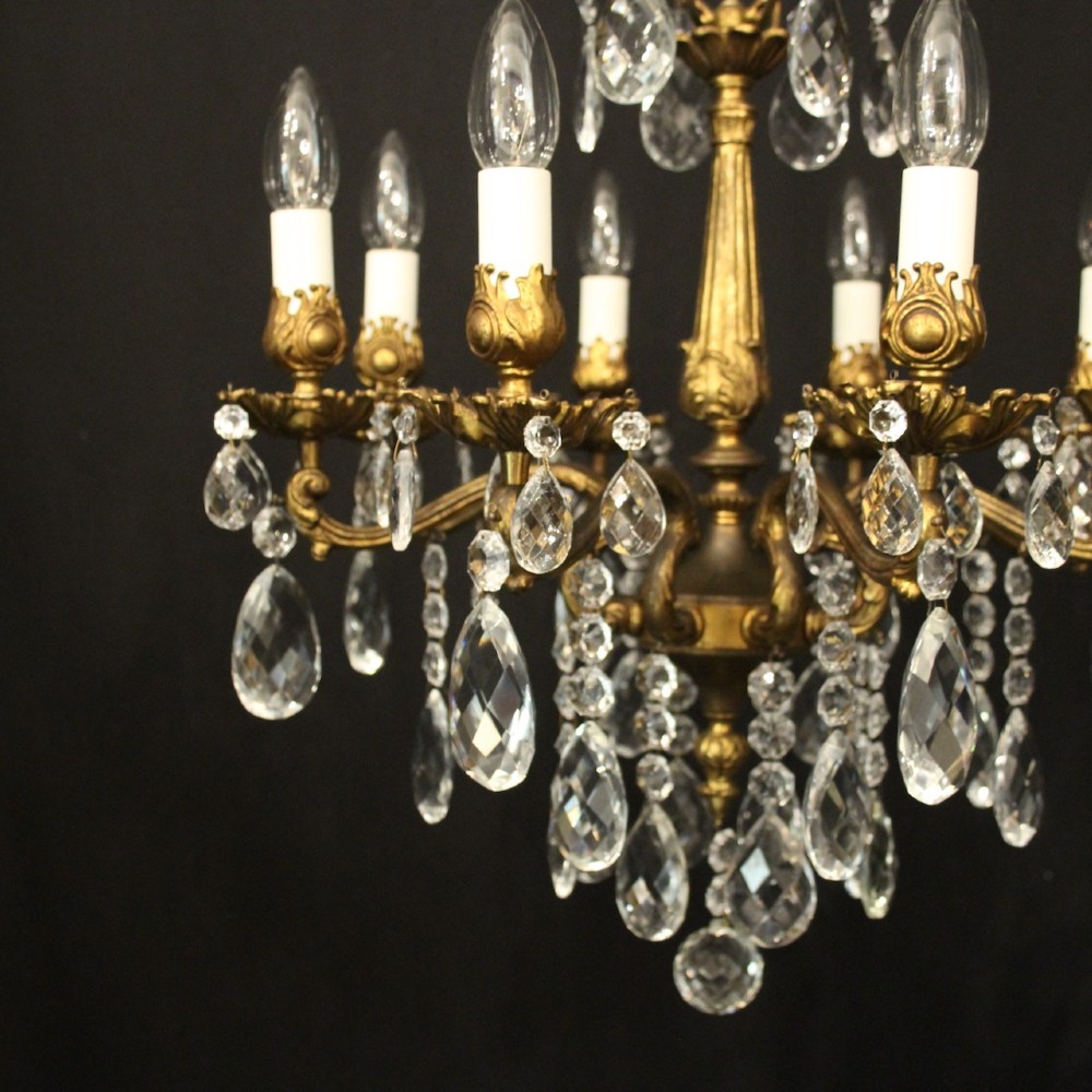 An eight-light antique French chandelier crafted from gilded metal featuring scrolling arms and clear cut glass crystal drops. View II