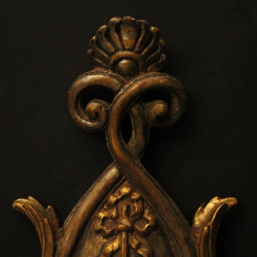 A pair of Florentine giltwood wall lights with twin curving arms, carved bow motifs, and faux candle bulb holders against a dark backdrop. View V