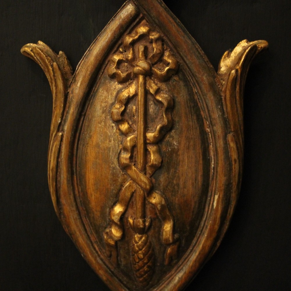 A pair of Florentine giltwood wall lights with twin curving arms, carved bow motifs, and faux candle bulb holders against a dark backdrop. View VII