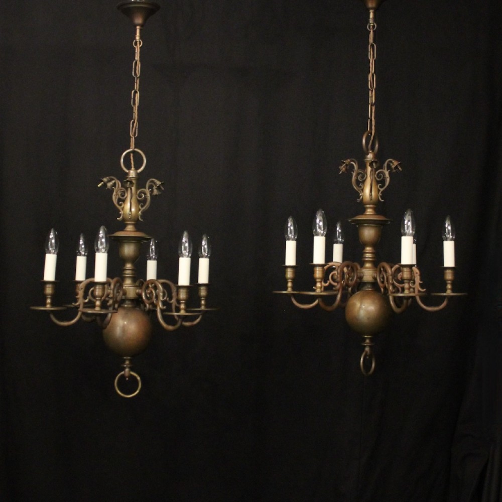 A pair of dark bronze six-light chandeliers featuring central turned baluster stems, lower spherical drops, and scrolling candle arms.