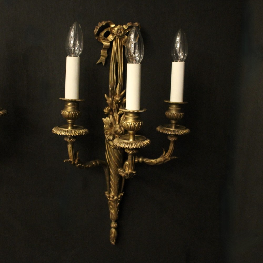 A pair of French gilt bronze three-light wall sconces featuring ribbon bow crests, tapered shafts, and scrolled candle branches. View II