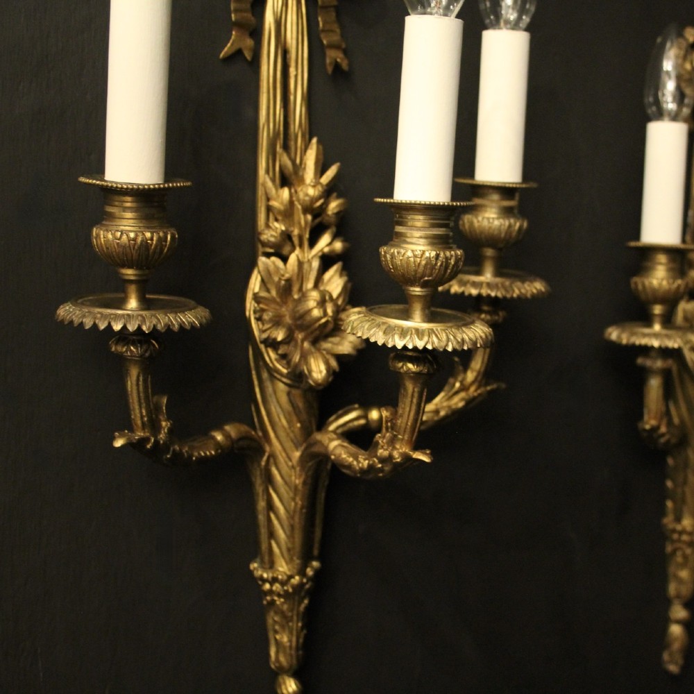 A pair of French gilt bronze three-light wall sconces featuring ribbon bow crests, tapered shafts, and scrolled candle branches. View III