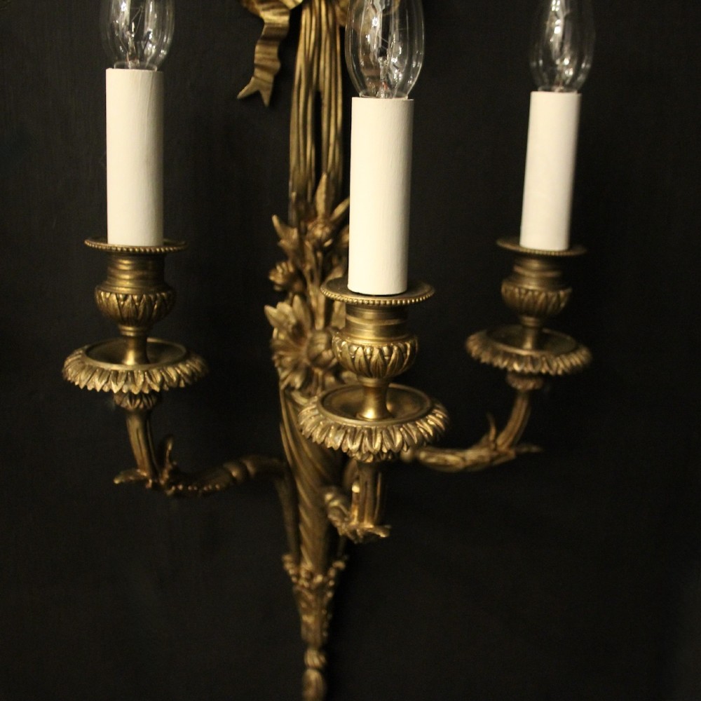 A pair of French gilt bronze three-light wall sconces featuring ribbon bow crests, tapered shafts, and scrolled candle branches. View VIII
