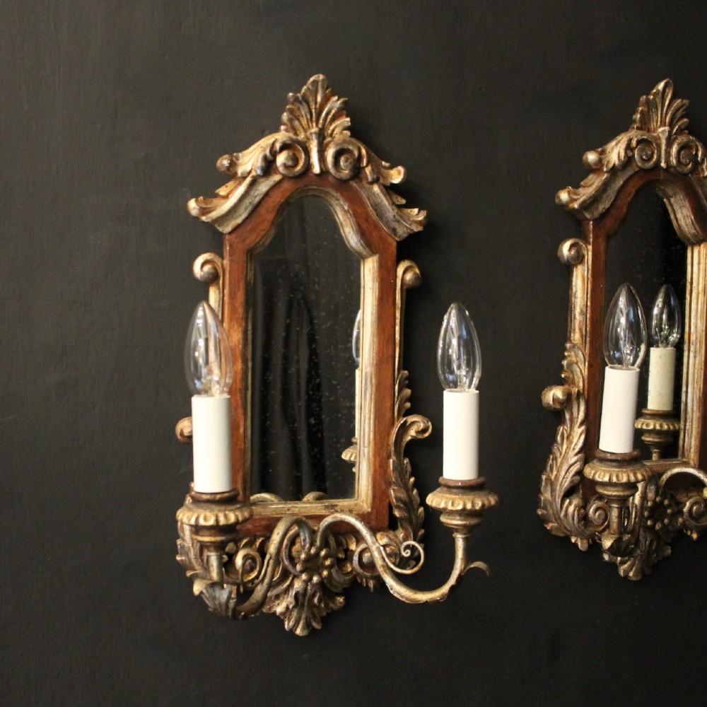 A pair of carved Florentine giltwood wall girandoles featuring arched mirror backplates, acanthus cresting, and twin light arms. View III