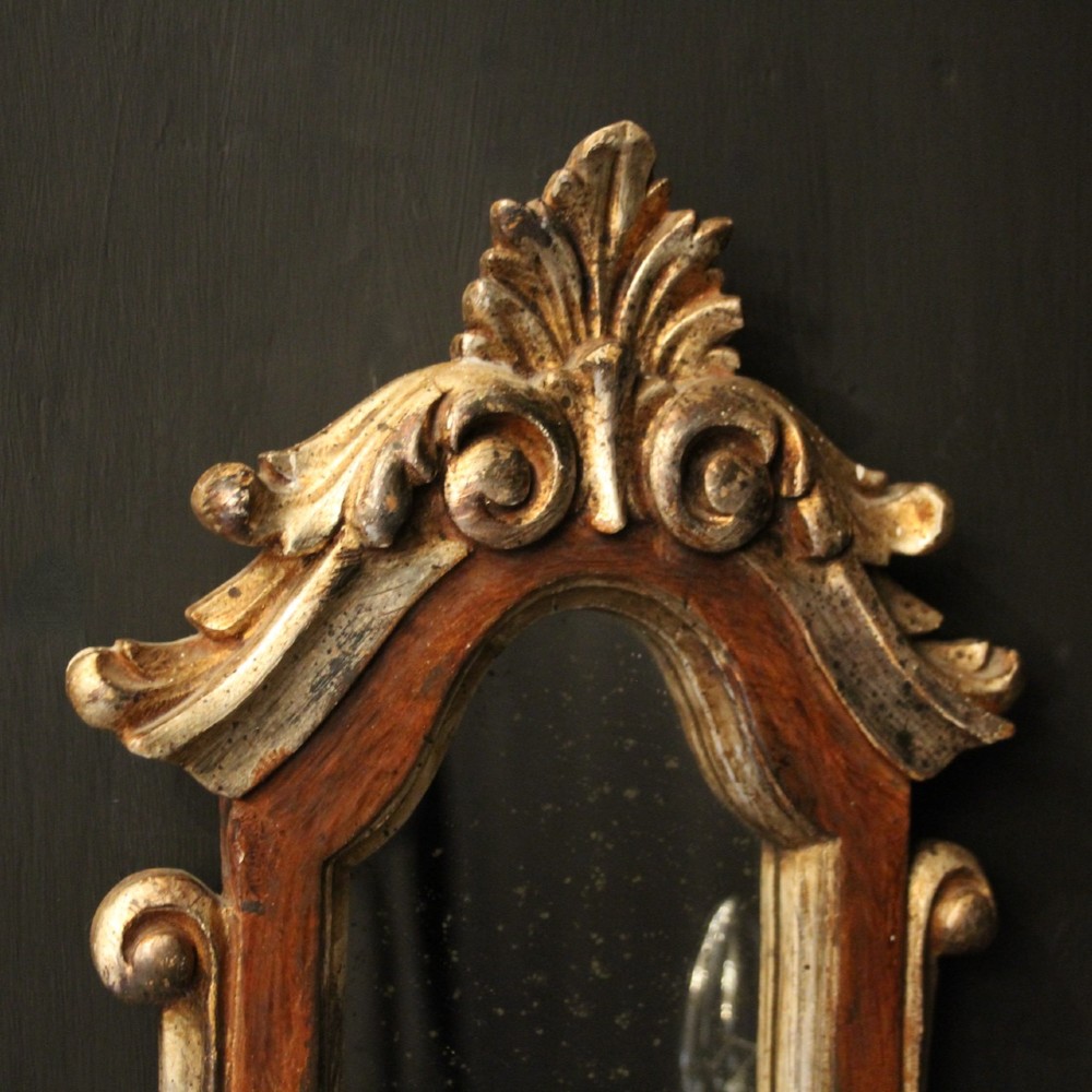 A pair of carved Florentine giltwood wall girandoles featuring arched mirror backplates, acanthus cresting, and twin light arms. View IV