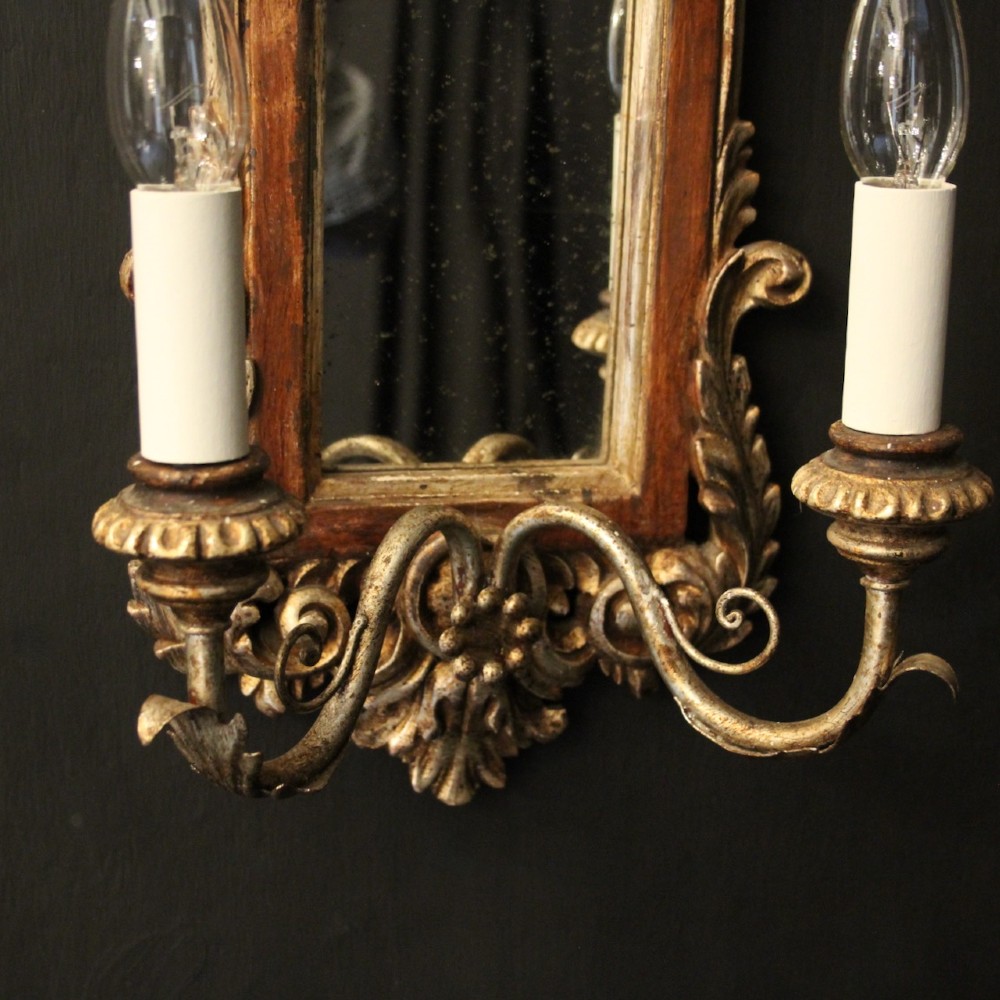 A pair of carved Florentine giltwood wall girandoles featuring arched mirror backplates, acanthus cresting, and twin light arms. View VI