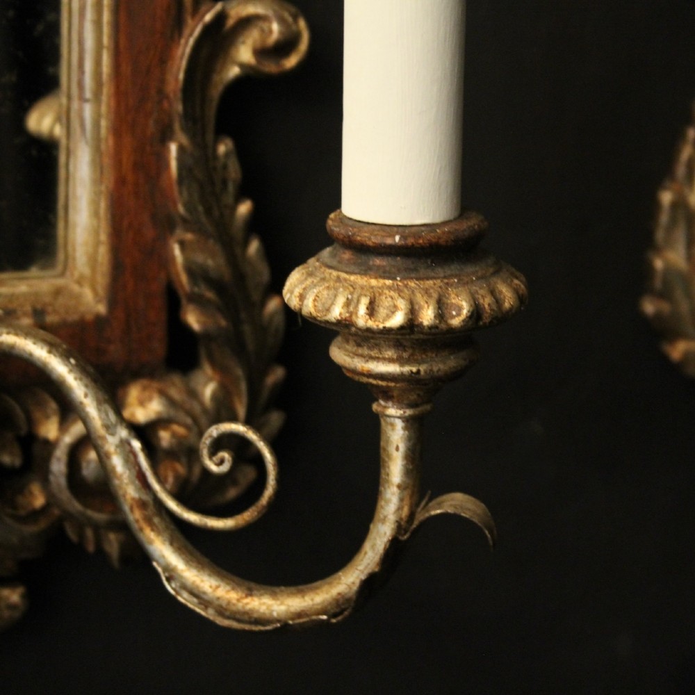 A pair of carved Florentine giltwood wall girandoles featuring arched mirror backplates, acanthus cresting, and twin light arms. View VII