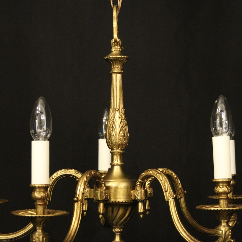 A French gilt bronze five-light chandelier featuring sweeping scroll arms, central fluted stem, decorative finial, and faux candle sleeves. View II