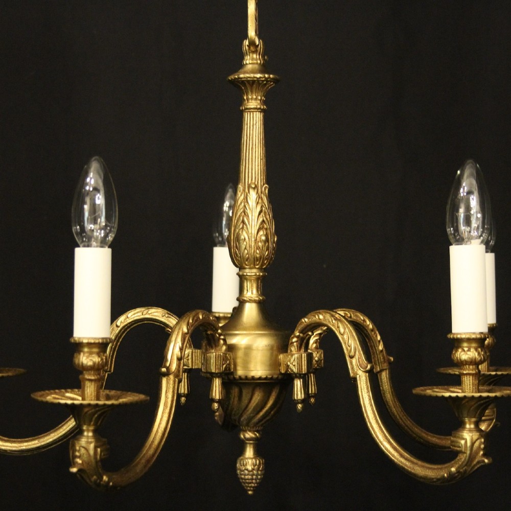 A French gilt bronze five-light chandelier featuring sweeping scroll arms, central fluted stem, decorative finial, and faux candle sleeves. View III