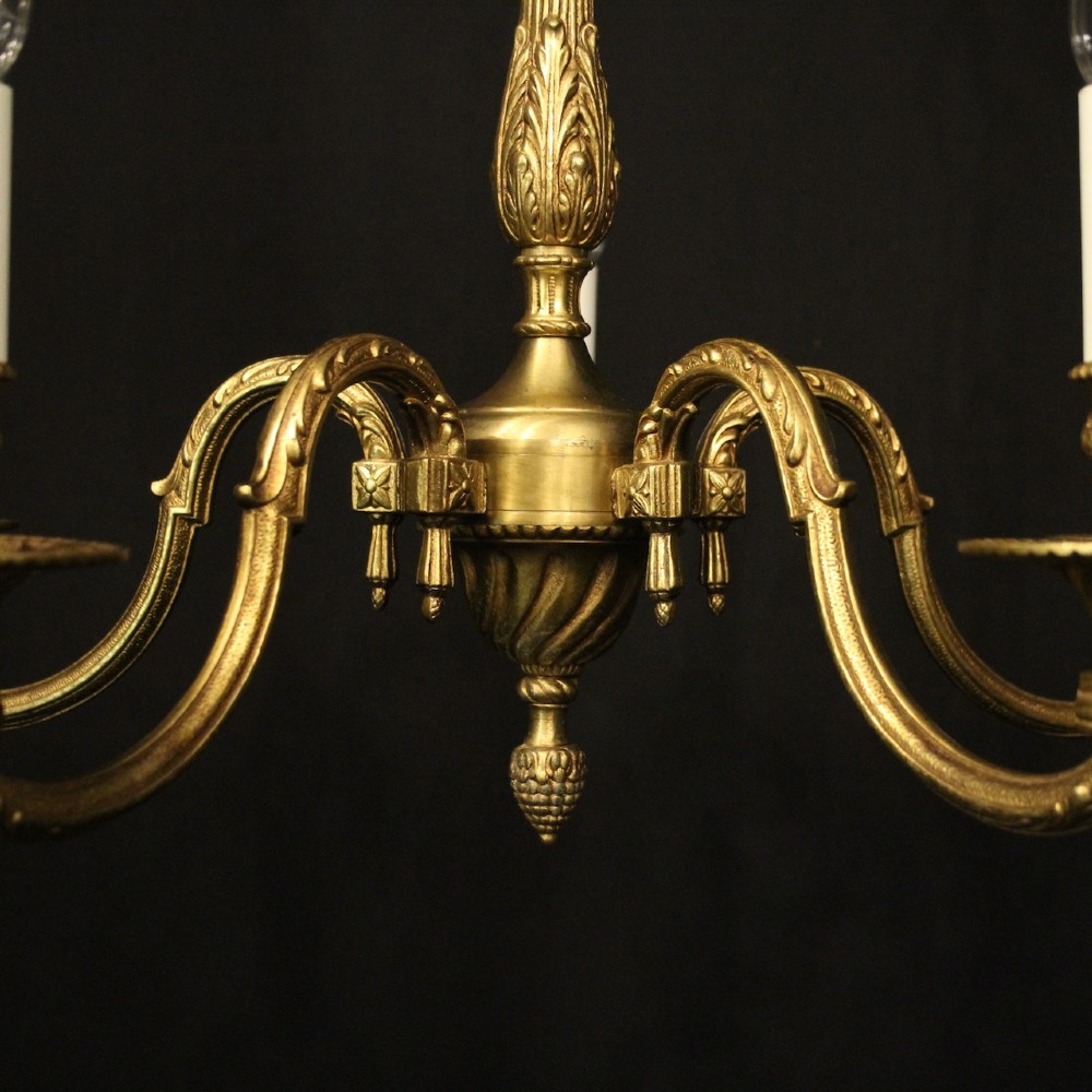 A French gilt bronze five-light chandelier featuring sweeping scroll arms, central fluted stem, decorative finial, and faux candle sleeves. View IV