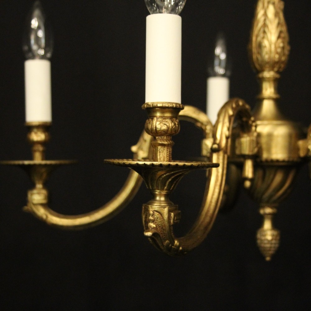 A French gilt bronze five-light chandelier featuring sweeping scroll arms, central fluted stem, decorative finial, and faux candle sleeves. View VI