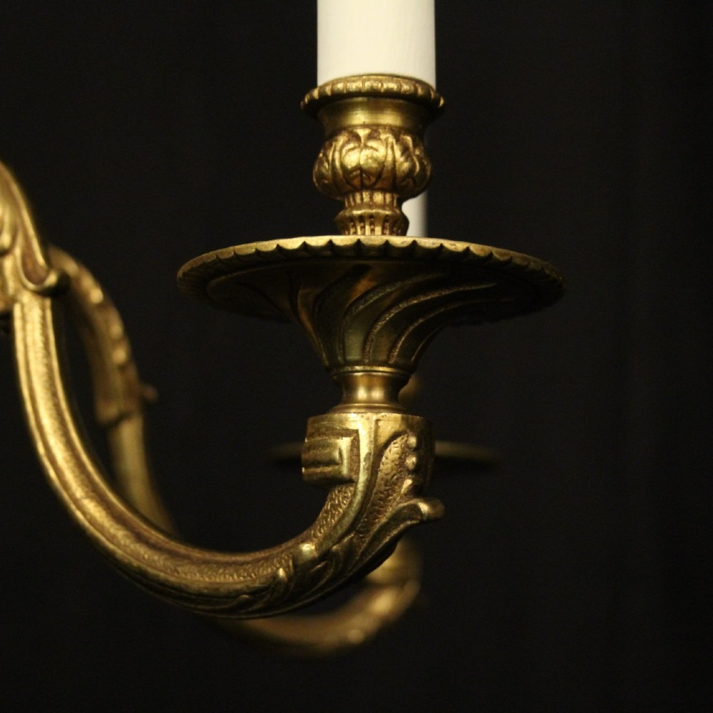 A French gilt bronze five-light chandelier featuring sweeping scroll arms, central fluted stem, decorative finial, and faux candle sleeves. View VII