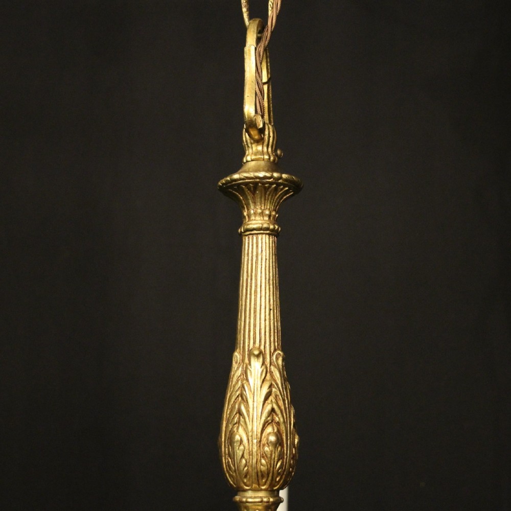 A French gilt bronze five-light chandelier featuring sweeping scroll arms, central fluted stem, decorative finial, and faux candle sleeves. View VIII