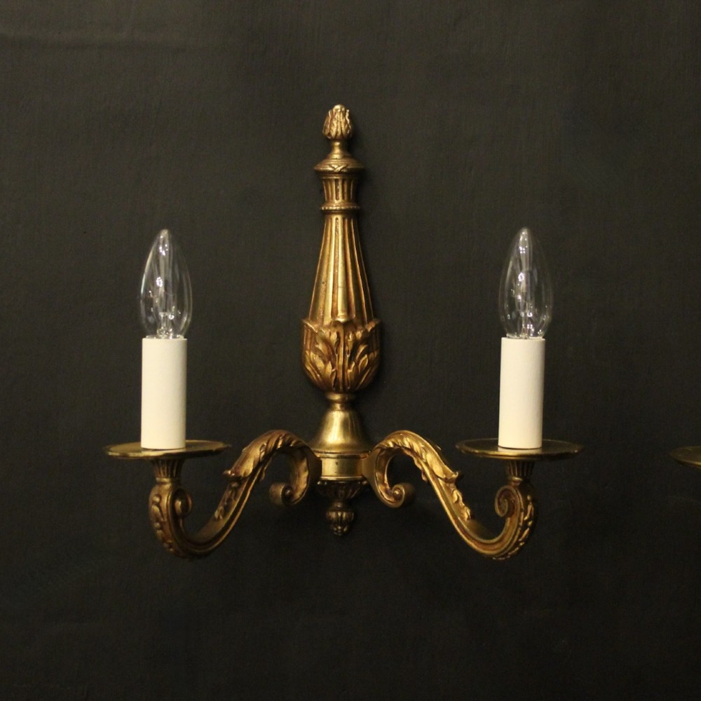 A pair of French Neoclassical gilded bronze twin-arm wall lights with acanthus leaf motifs, central fluted columns, and candle-style fittings. View II