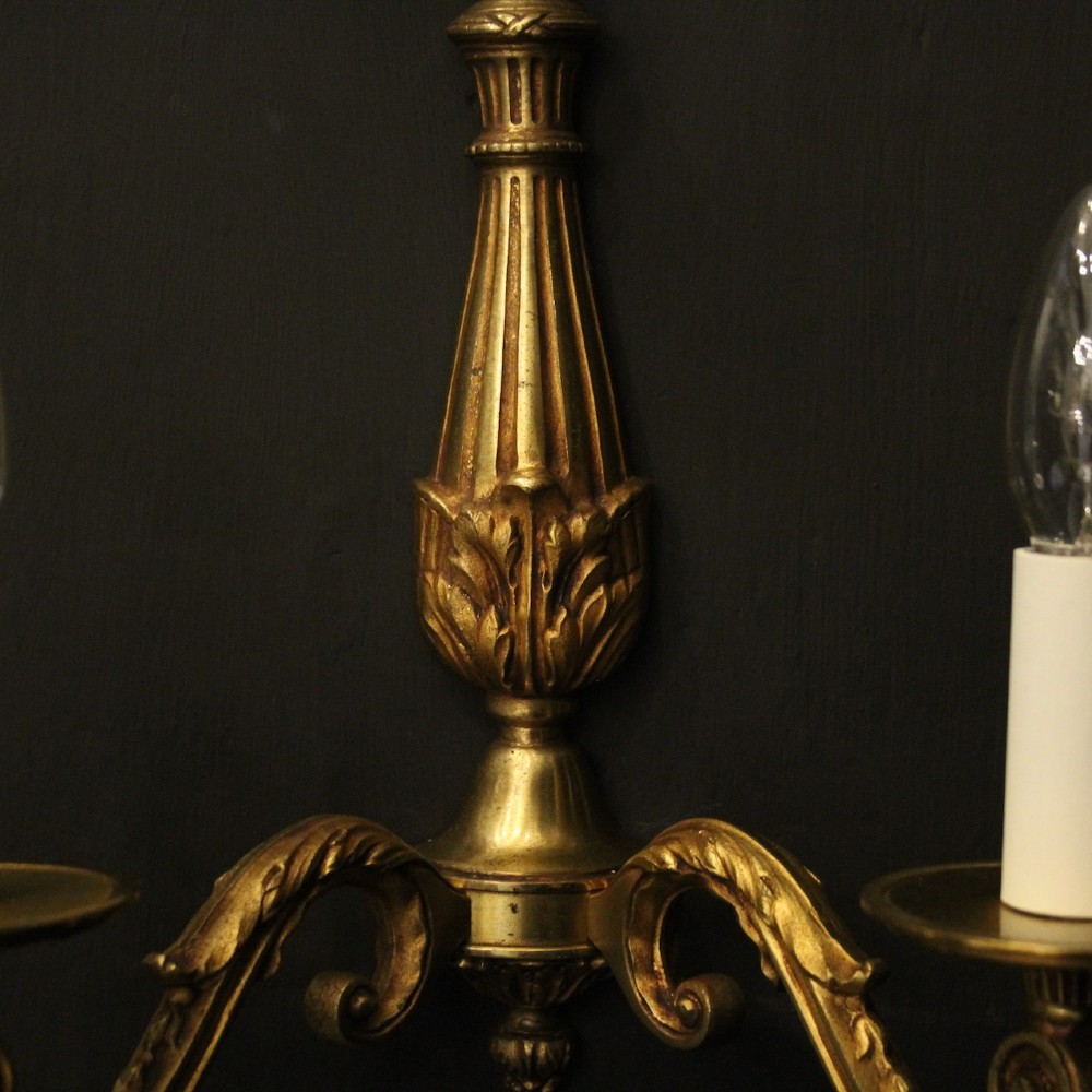 A pair of French Neoclassical gilded bronze twin-arm wall lights with acanthus leaf motifs, central fluted columns, and candle-style fittings. View VI