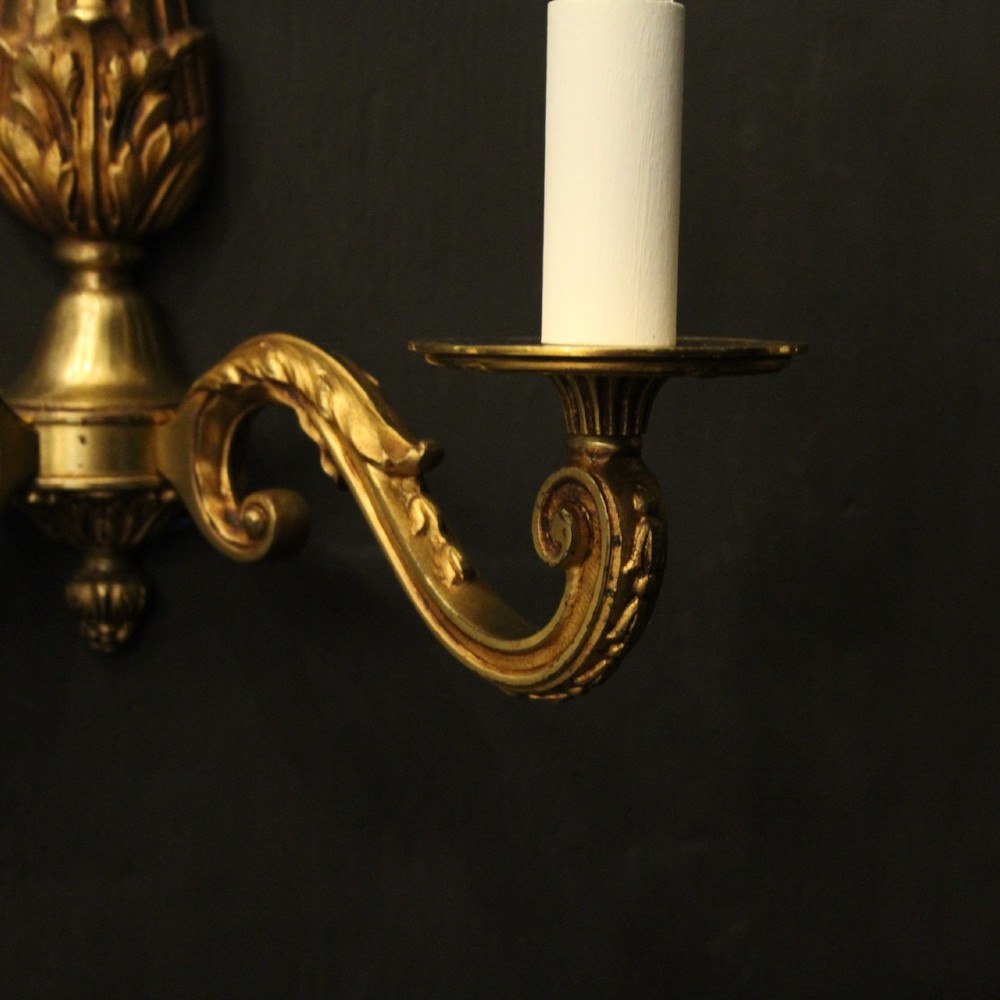 A pair of French Neoclassical gilded bronze twin-arm wall lights with acanthus leaf motifs, central fluted columns, and candle-style fittings. View VII