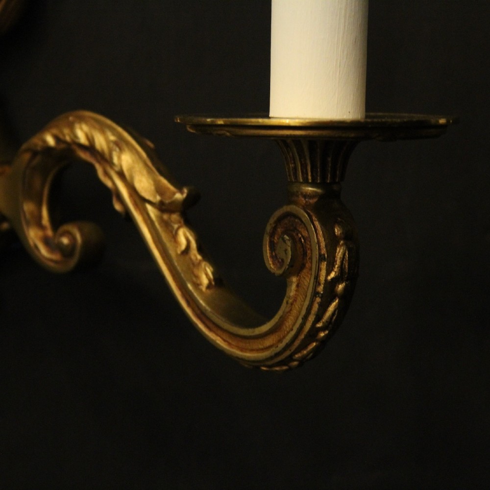 A pair of French Neoclassical gilded bronze twin-arm wall lights with acanthus leaf motifs, central fluted columns, and candle-style fittings. View VIII
