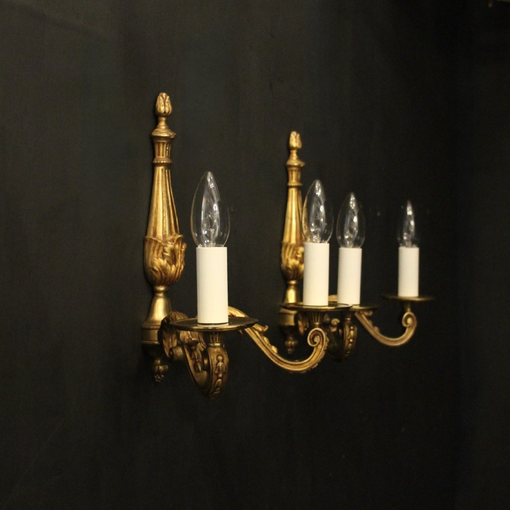 A pair of French Neoclassical gilded bronze twin-arm wall lights with acanthus leaf motifs, central fluted columns, and candle-style fittings. View X