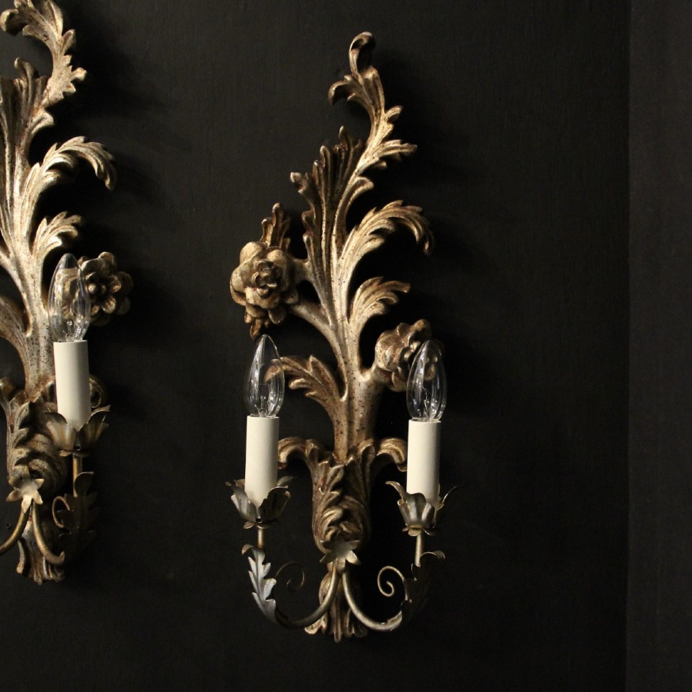 A pair of carved Florentine silver giltwood twin-arm wall sconces featuring acanthus leaf motifs and candle-style bulbs. View II