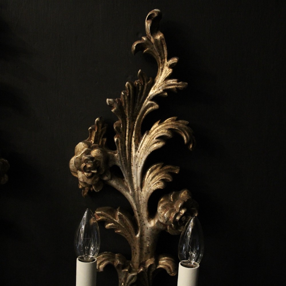 A pair of carved Florentine silver giltwood twin-arm wall sconces featuring acanthus leaf motifs and candle-style bulbs. View III