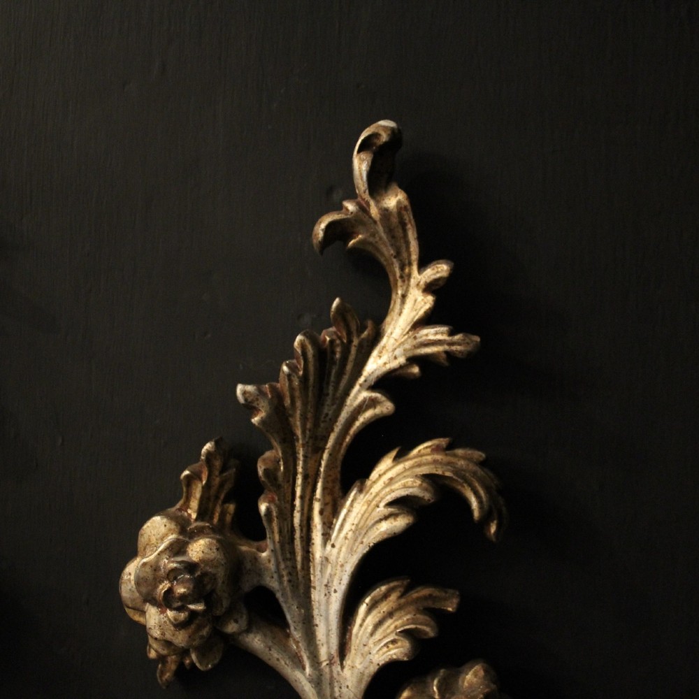 A pair of carved Florentine silver giltwood twin-arm wall sconces featuring acanthus leaf motifs and candle-style bulbs. View IV
