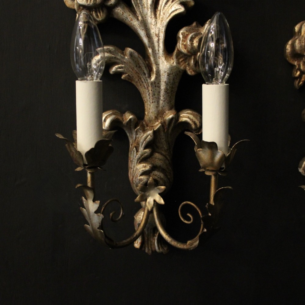A pair of carved Florentine silver giltwood twin-arm wall sconces featuring acanthus leaf motifs and candle-style bulbs. View VIII