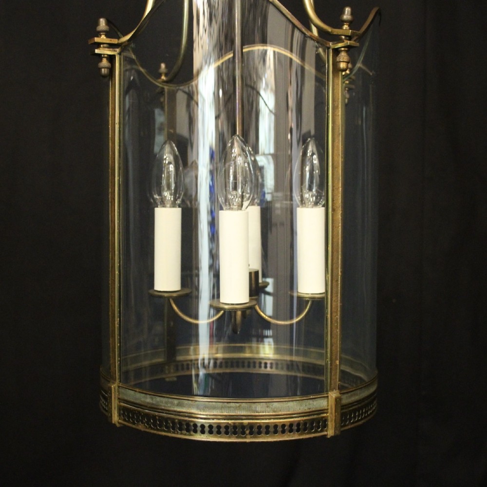 A hanging gilt brass hall lantern featuring curved convex glass panels and an internal four-candle light cluster supported by a central chain. View II