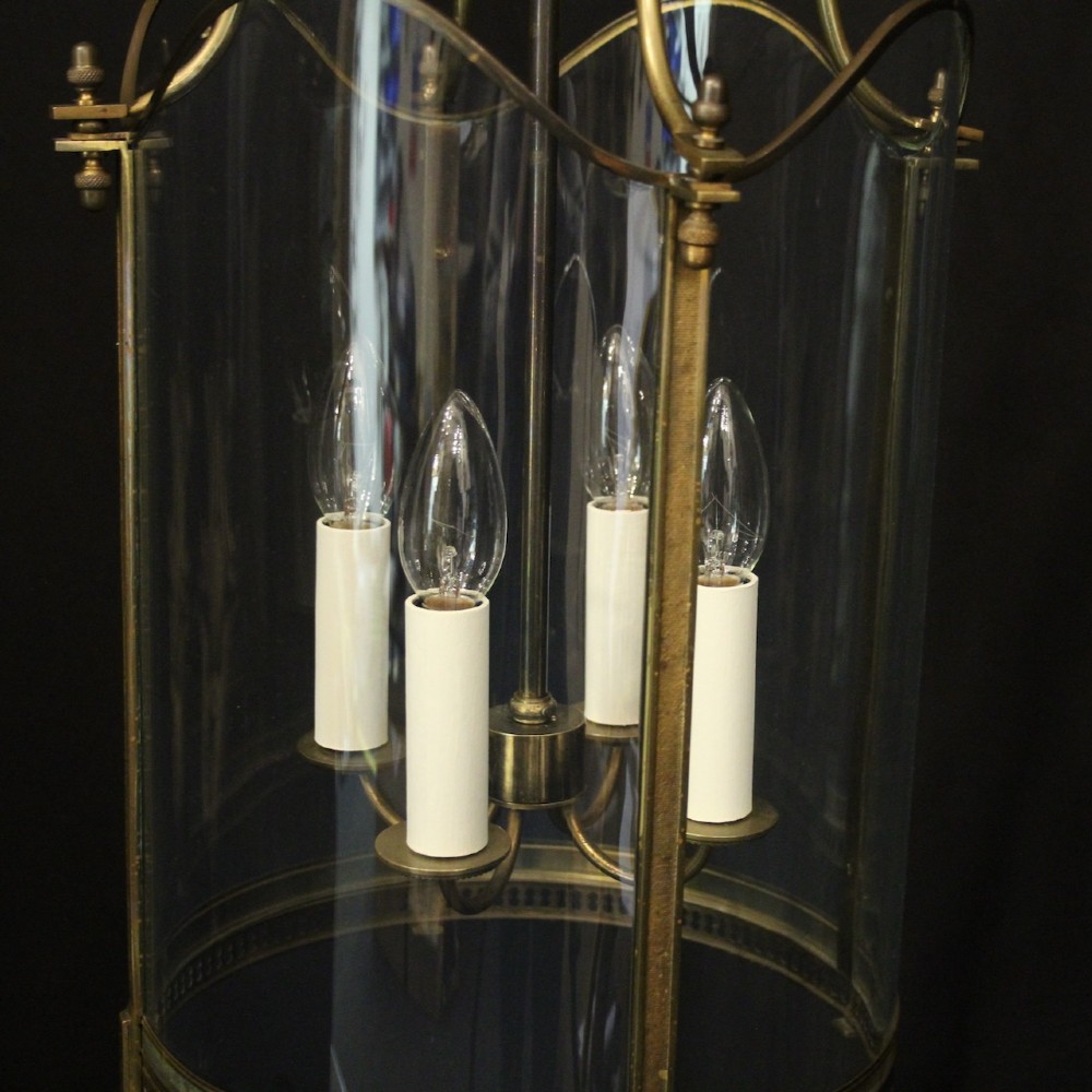 A hanging gilt brass hall lantern featuring curved convex glass panels and an internal four-candle light cluster supported by a central chain. View III