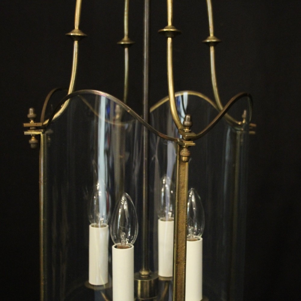 A hanging gilt brass hall lantern featuring curved convex glass panels and an internal four-candle light cluster supported by a central chain. View V