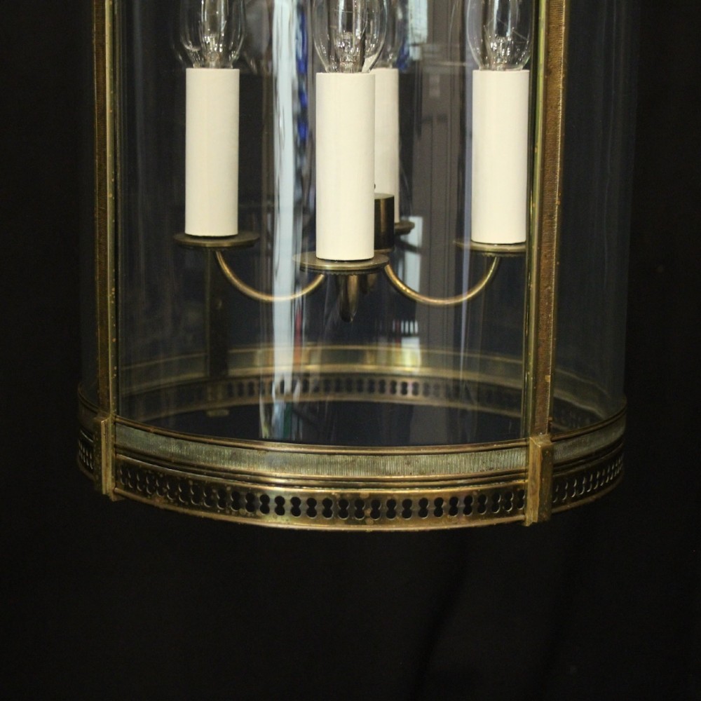 A hanging gilt brass hall lantern featuring curved convex glass panels and an internal four-candle light cluster supported by a central chain. View VIII