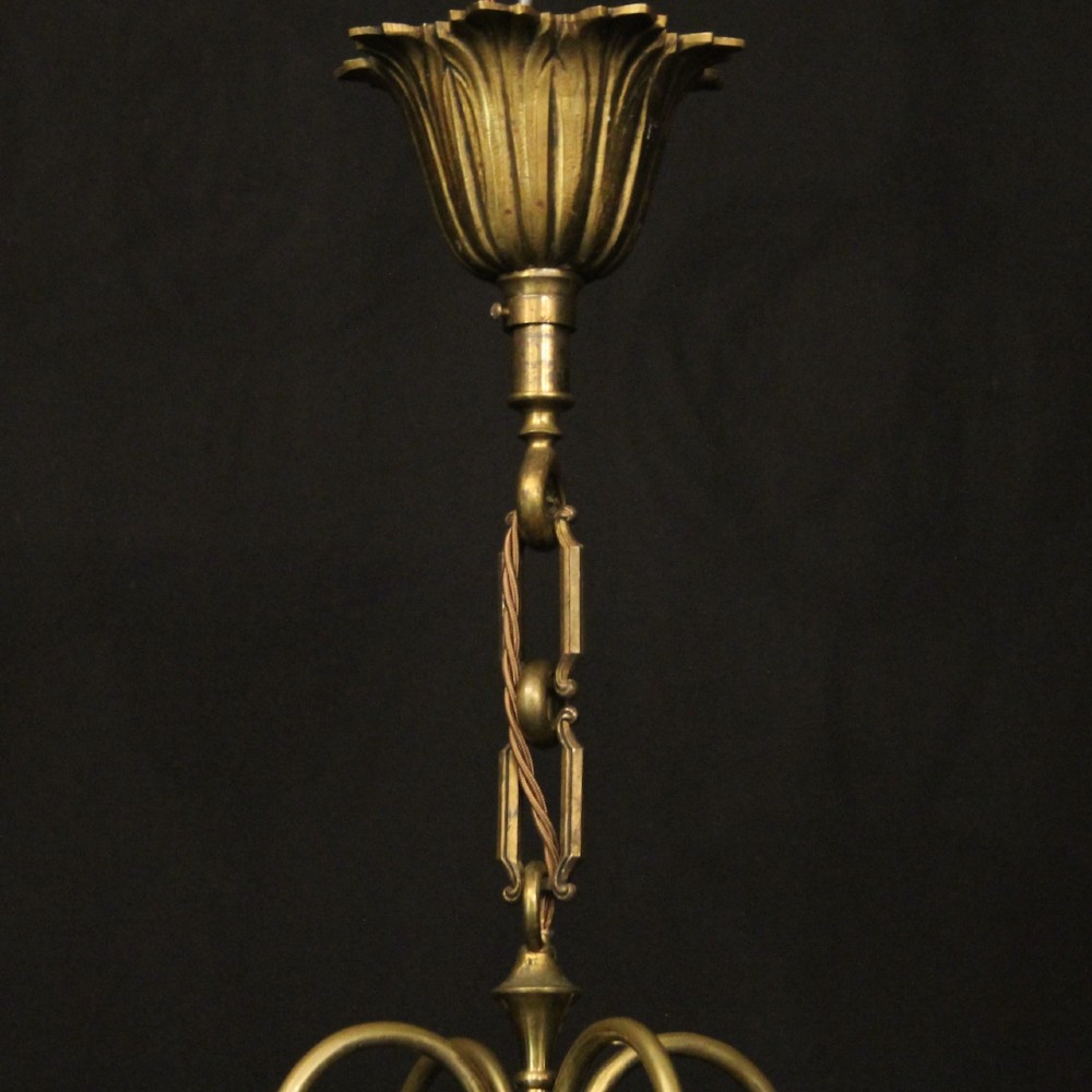 A hanging gilt brass hall lantern featuring curved convex glass panels and an internal four-candle light cluster supported by a central chain. View X