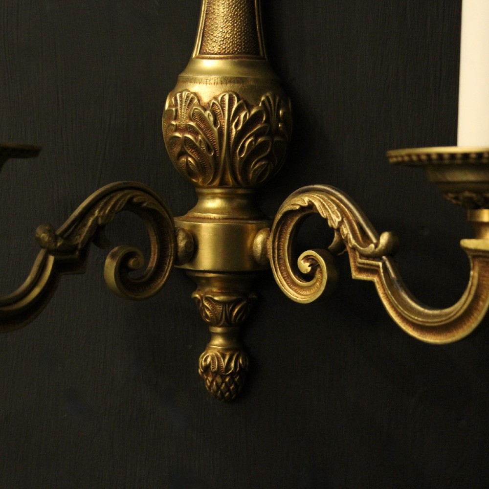 A set of four French gilded brass twin-arm wall sconces featuring scrolled arms, leaf motifs, and flame finials. View III