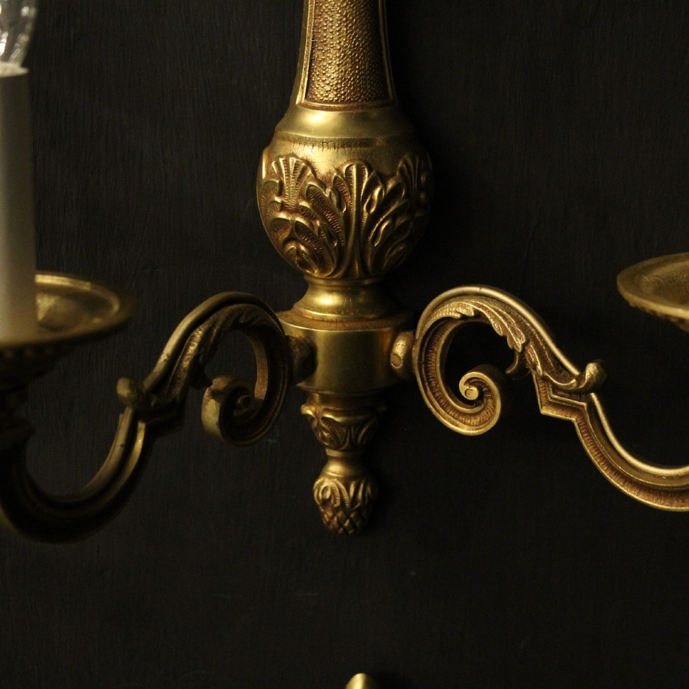 A set of four French gilded brass twin-arm wall sconces featuring scrolled arms, leaf motifs, and flame finials. View VIII