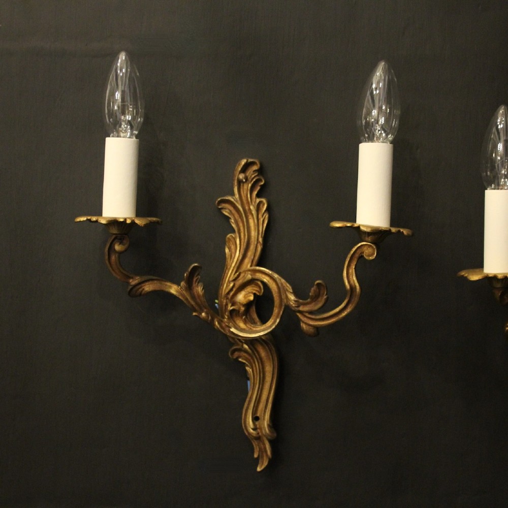 A set of four antique French twin-arm wall sconces crafted from gilded metal featuring ornate acanthus leaf scrolls. View II