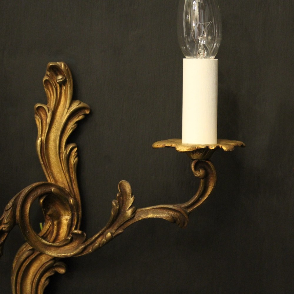 A set of four antique French twin-arm wall sconces crafted from gilded metal featuring ornate acanthus leaf scrolls. View IV