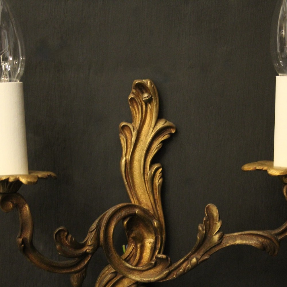 A set of four antique French twin-arm wall sconces crafted from gilded metal featuring ornate acanthus leaf scrolls. View V