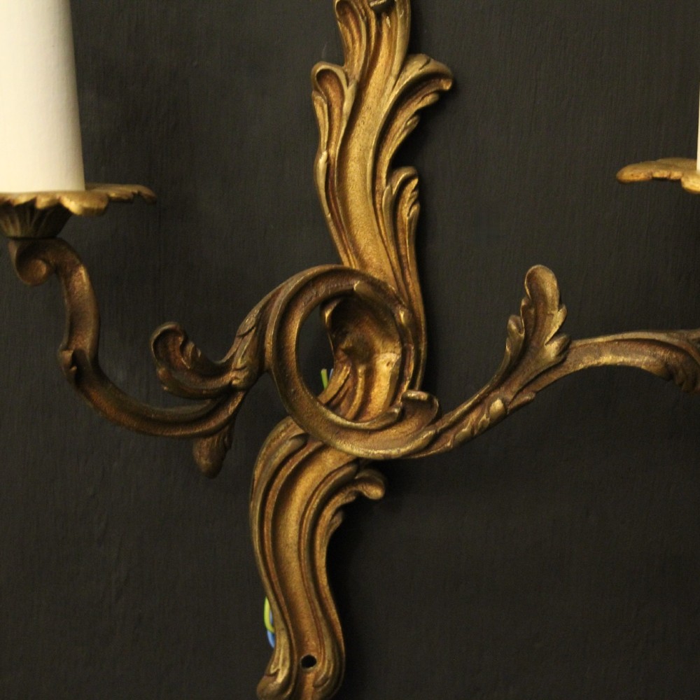 A set of four antique French twin-arm wall sconces crafted from gilded metal featuring ornate acanthus leaf scrolls. View VI