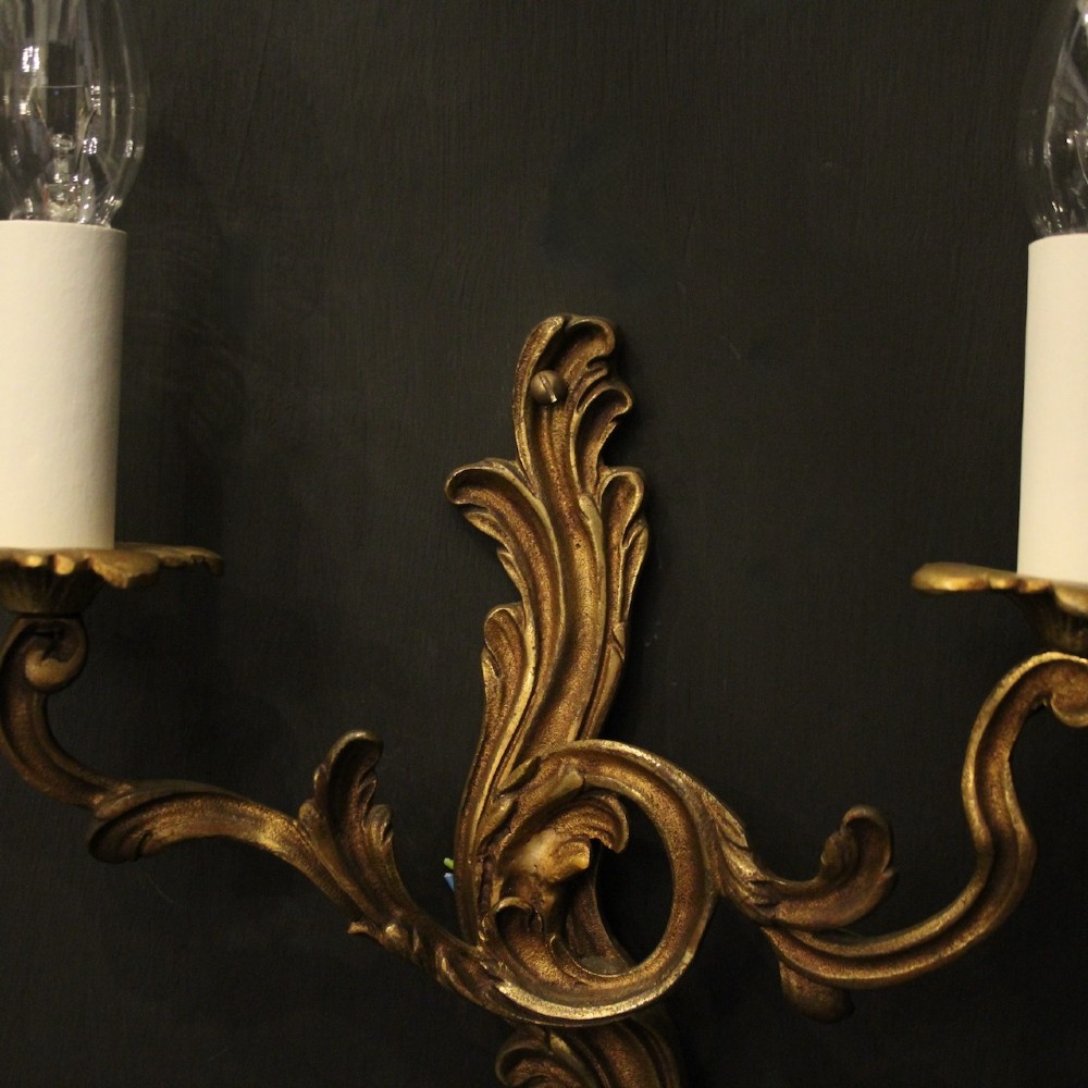 A set of four antique French twin-arm wall sconces crafted from gilded metal featuring ornate acanthus leaf scrolls. View VIII