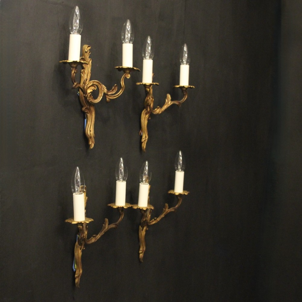 A set of four antique French twin-arm wall sconces crafted from gilded metal featuring ornate acanthus leaf scrolls. View X