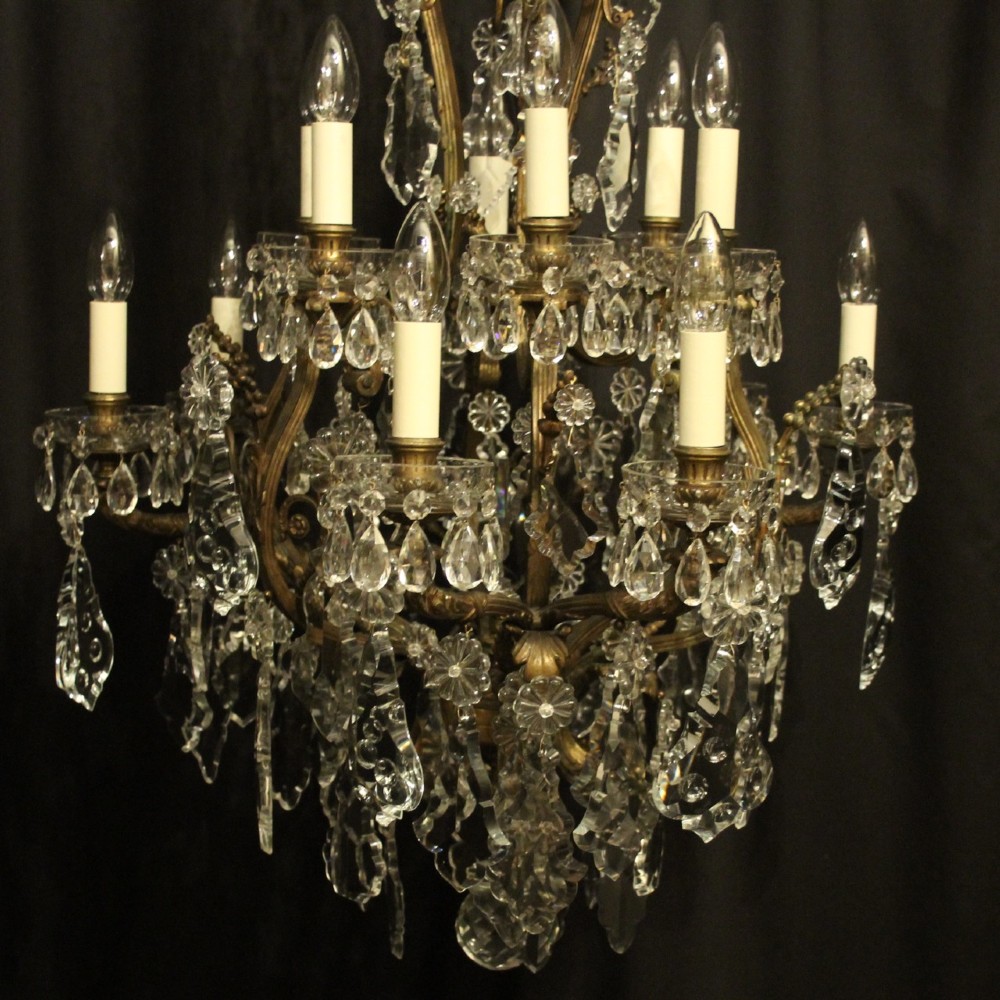 A French gilded bronze twelve-light chandelier featuring a scrollwork frame draped with faceted crystal drops and glass rosettes. View II
