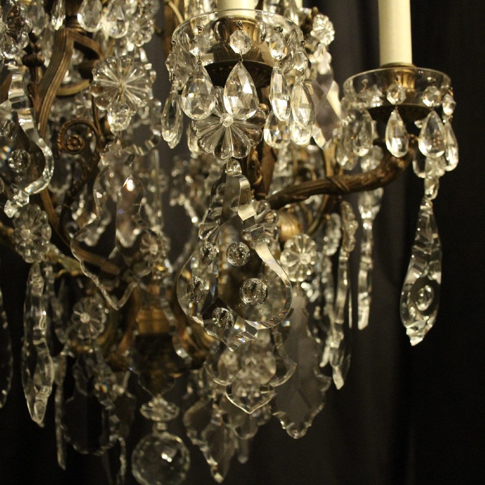 A French gilded bronze twelve-light chandelier featuring a scrollwork frame draped with faceted crystal drops and glass rosettes. View III