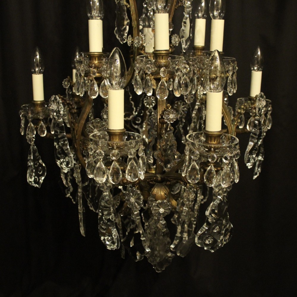 A French gilded bronze twelve-light chandelier featuring a scrollwork frame draped with faceted crystal drops and glass rosettes. View V