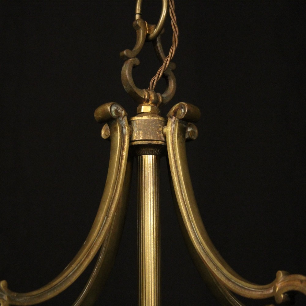 A cylindrical gilded bronze hall lantern with curved clear glass panels and four internal candle bulb fittings hanging from a chain. View IX