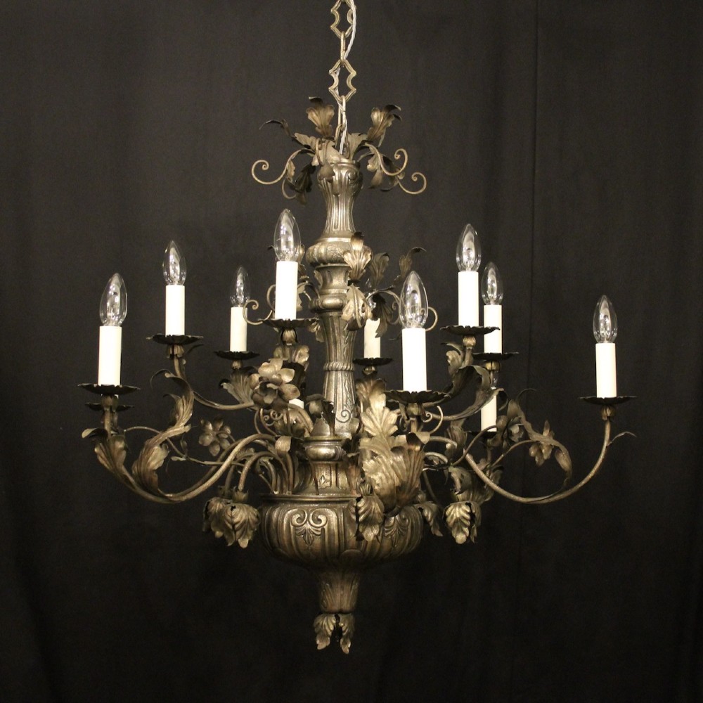 An antique Italian Genoa twelve-light chandelier crafted from gilded metal featuring ornate leaf motifs and scrolling arms supporting candle bulb holders.
