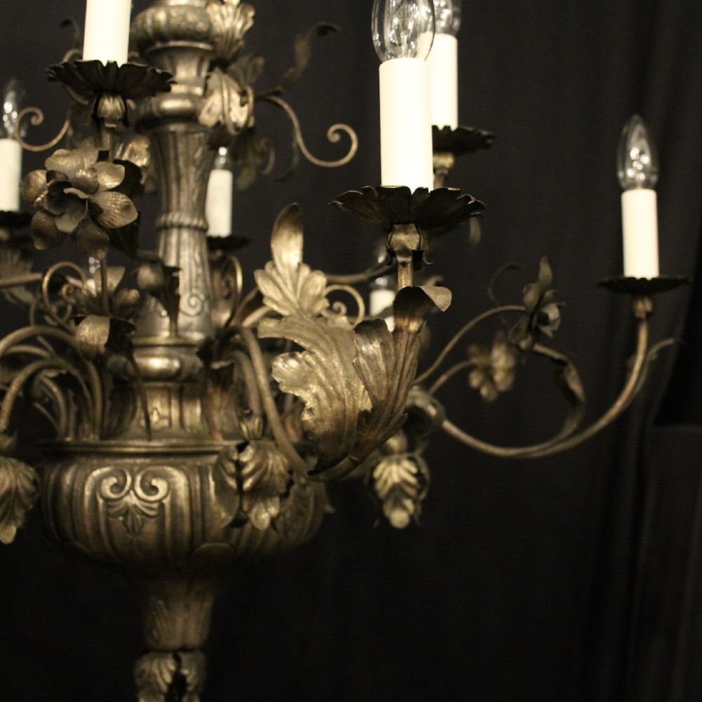 An antique Italian Genoa twelve-light chandelier crafted from gilded metal featuring ornate leaf motifs and scrolling arms supporting candle bulb holders. View II