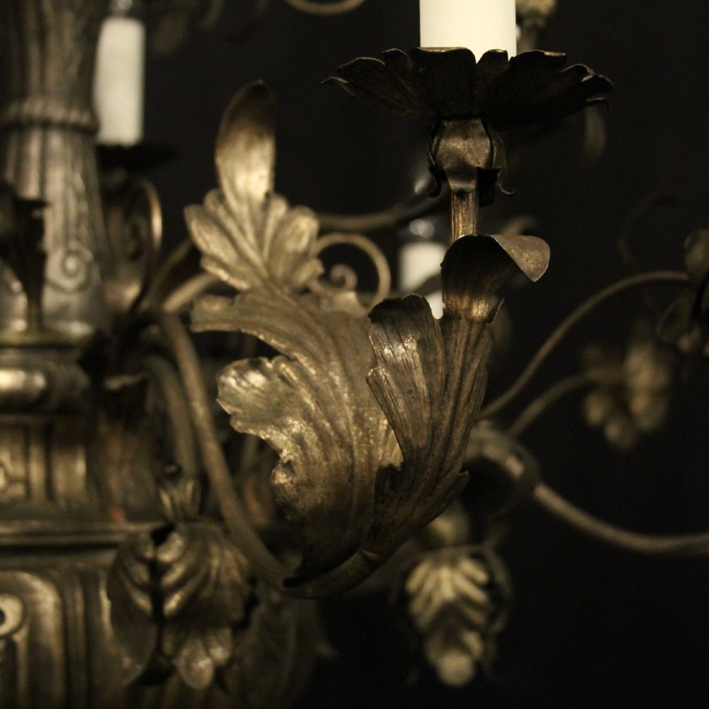 An antique Italian Genoa twelve-light chandelier crafted from gilded metal featuring ornate leaf motifs and scrolling arms supporting candle bulb holders. View III